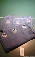 Folded pair of blue woven curtain panels showing grommets