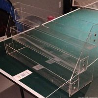 Front angled view of clear acrylic 3-tier rack showing side supports and three shelves