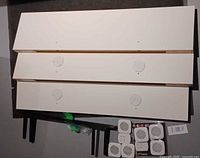 Three stacked white floating shelves with four LED light bases attached and six LED puck lights shown separately