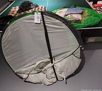 Collapsed pop-up tent with strap, plaid blanket, additional accessories on table