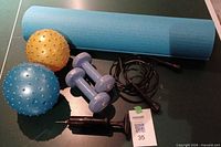 Group shot showing blue yoga mat, two spiky balls, hand pump, pair 3 lb dumbbells, black jump rope
