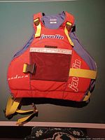 Front view of life jacket showing color scheme, straps, buckle, logos, mesh pocket