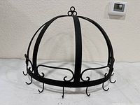Full front view of black cast iron dome hanging utensil rack showing overall design