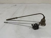 Brass bell snuffer and castle-dragon snuffer side by side