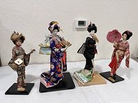 Front view of four geisha dolls showing clothing and accessories