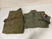 Shirt and gear bag side by side showing identifying markings and patches