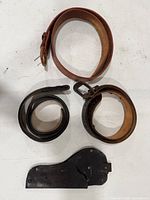 Overview of three rolled belts and holster laid flat