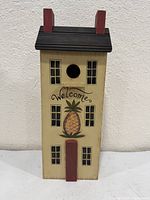 Front view showing pineapple motif, "Welcome" text, entry hole, windows