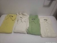 Front view of four folded polo shirts displaying colours and collars