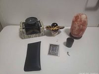 Group shot of all items: salt lamp, mini grill, skull with sombrero, rhinestone pendant, black pouch, trading card, tealight cup