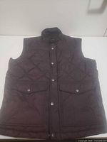 front view of dark brown quilted vest showing pockets, snaps, zipper