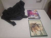 All three items laid out: black sling bag and two books