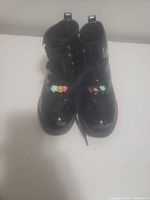 Top view of both black patent platform boots showing laces and decorative patches
