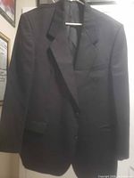 Front view of black single-breasted suit jacket on hanger
