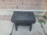Top view of black wooden stool against brick wall