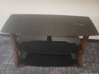 Front view of entire TV stand showing three glass shelves and wood legs