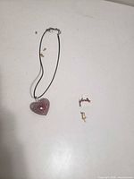 Necklace, earrings, pendant laid on white surface