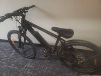 Full left-side view of black e-bike showing frame, battery, wheels, pedals, handlebar