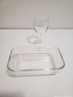 rectangular glass butter dish and stemmed wine glass on white surface
