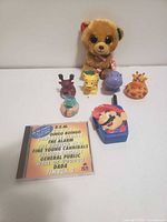 Group shot showing all items: Ty bear, Little People animals, Mario walkie talkie, CD
