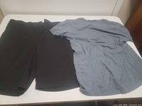 Black pants and blue t-shirt laid side by side on table