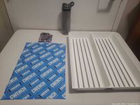 All four items laid out: bottle, dish tray, towel, laces