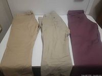 Three pairs chinos laid flat showing full length and colors khaki, beige, burgundy