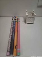 Four rolled poster tubes beside white ceramic planter
