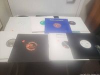 Seven vinyl singles laid out showing sleeve colours and label cut-outs