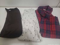 Three folded shirts: brown H&M tee, grey Old Navy printed tee, red/blue plaid button-up