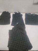 All four garments laid out: two plaid pieces and two striped shirts visible