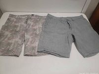 Both pairs of shorts side by side: left tropical print, right blue-grey stripe