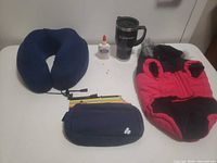 Group shot showing all five items: dog coat, neck pillow, travel mug, glue bottle, wristlet pouch
