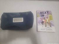 Front view of cosmetic bag beside book front cover