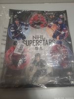 Front view of poster in plastic showing all six players and NHL Superstars title