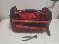 Front view of Olympia Tools open-top red/black tool bag with pliers placed in front