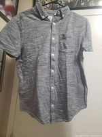 Front view of striped shirt showing buttons, pocket, logo