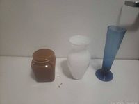 All three items: blue vase, white vase, brown jar with lid