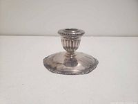 Front view of silver-plated candle holder showing fluted cup and decorative base