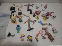 Group overview of all approximately 30 assorted figurines and keychain items spread on tabletop