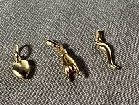 three gold pendants heart, hand, horn