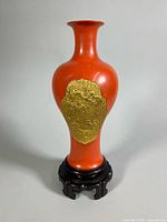Front view of red lacquer vase on stand showing gold dragon panel