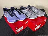 Both pairs of shoes on top of their red New Balance boxes