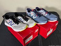 Both pairs on top of original red New Balance boxes