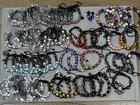 Overview of entire lot showing assorted Shamballa bracelets, evil-eye bracelets and stud earrings