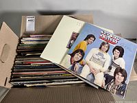 Box filled with stacked LPs; signed Bay City Rollers album displayed on top