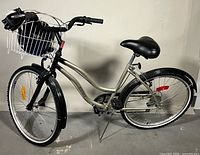 Full left-side view of silver Mystique cruiser bicycle with wire basket and helmets