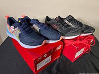 Both pairs of shoes on their red New Balance boxes