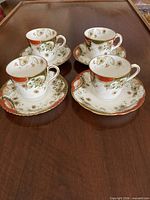 Four demitasse cups with matching saucers on table