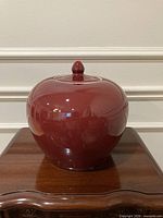 Front view of red glazed ginger jar on wooden stand